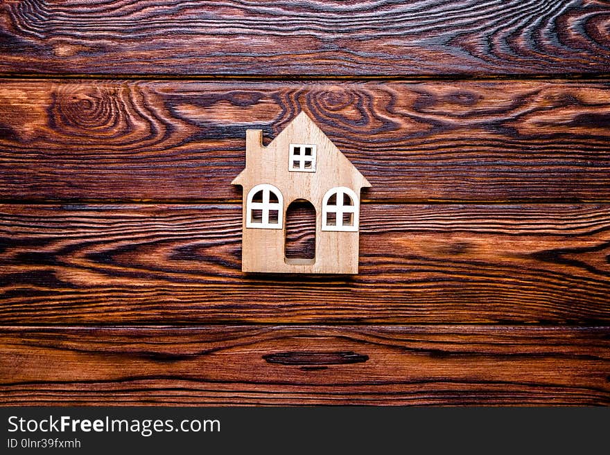 The symbol of the house stands on a brown wooden background