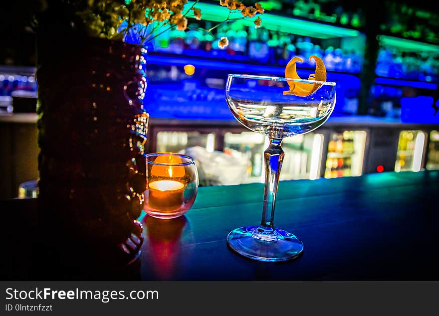 Clean cocktail glass set on top of a busy tropical bar ready for delicious beverages to be poured in. Drink up!. Clean cocktail glass set on top of a busy tropical bar ready for delicious beverages to be poured in. Drink up!