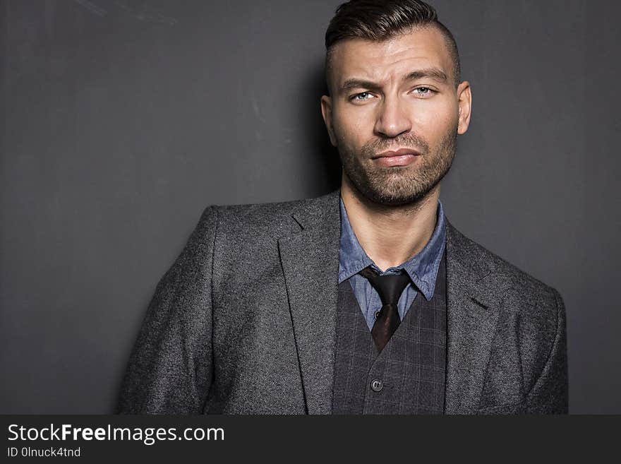 Portrait of stylish, elegant young man in suit with an impudent and prejudiced expression. Brutal young businessman.