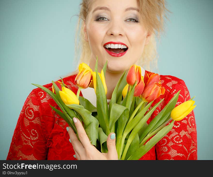 International woman day, eight march. Beautiful portrait of pretty woman blonde hair with red yellow tulips, fashion make up, elegant outfit. Mother day. On blue. International woman day, eight march. Beautiful portrait of pretty woman blonde hair with red yellow tulips, fashion make up, elegant outfit. Mother day. On blue