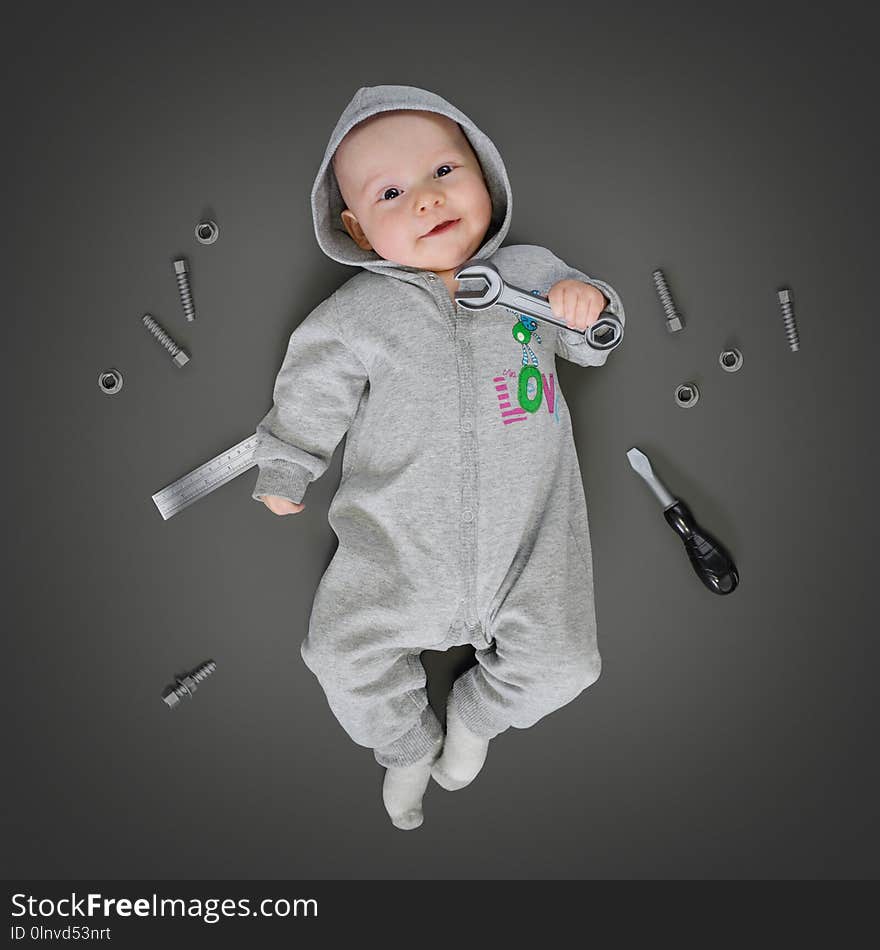 Baby in grey costume lying on a play mat and pretending he is a real repairer