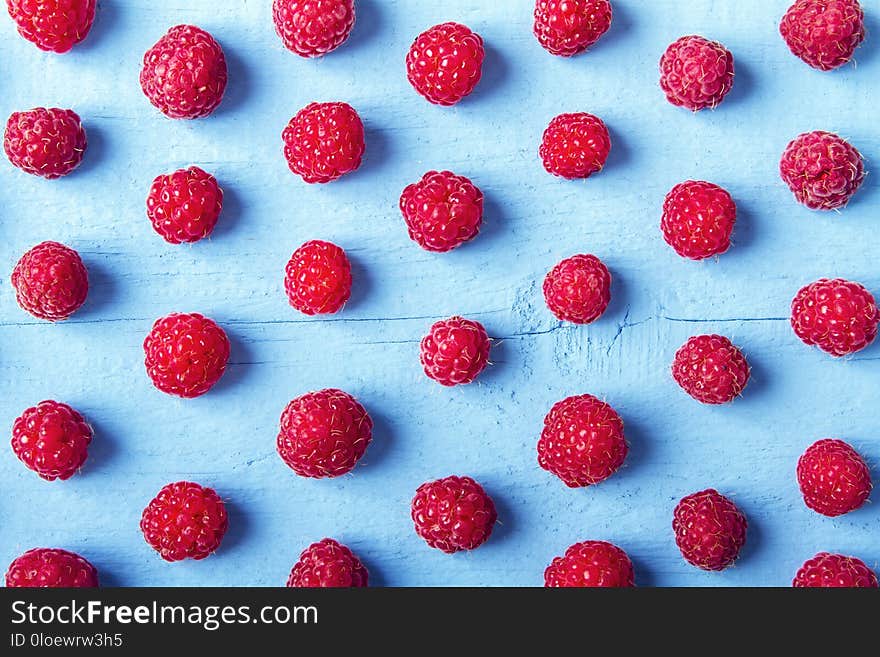 Many fresh raspberries on blue wooden background. Bright texture for design. Top view.