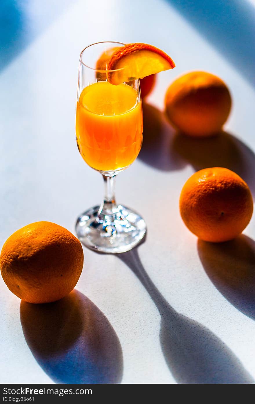 Fresh vivid colorful oranges on a white table and a glass of freshly squised orange juice. Copy space.