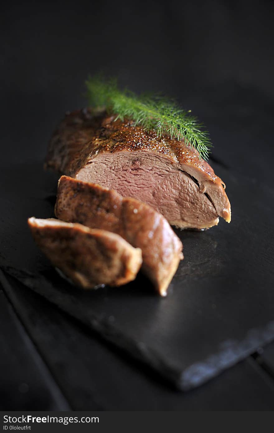 Fillet of meat on a black board and fresh greens