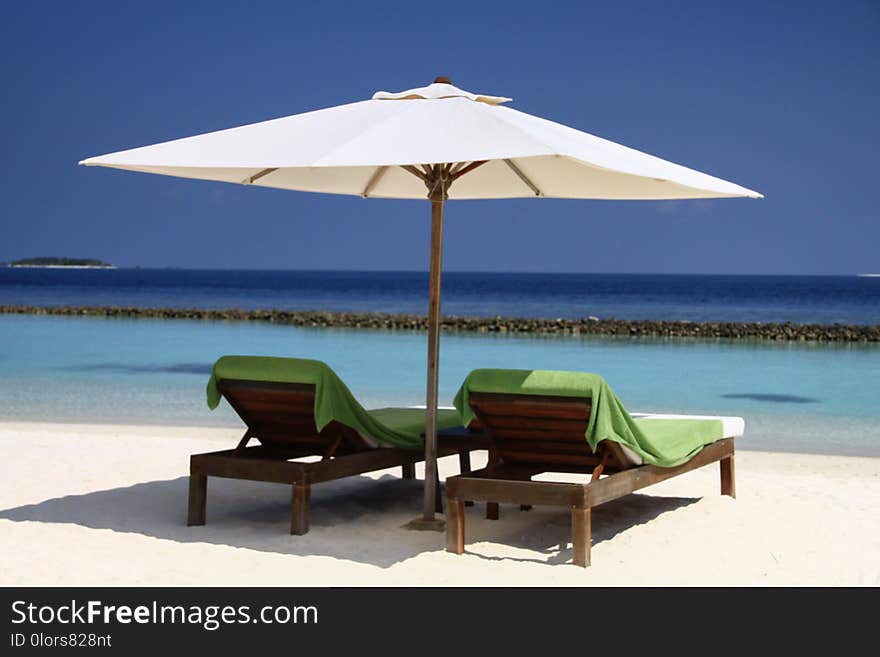 Wooden Seats, Palm Trees and Pacific Ocean in Luxury Maldives Resort with Blue Sky