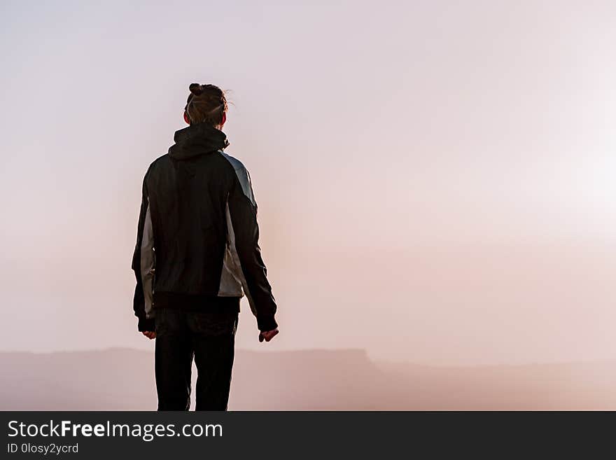 Alone man in israel negev desert admires the view of sunrise. Young male person stands on the edge of the cliff of makhtesh ramon park. Beautiful horizon landscape