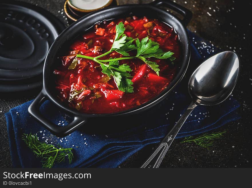 Ukrainian Russian traditional hot dish - borsch soup, with greens, garlic, rye bread, on a dark table. Ukrainian Russian traditional hot dish - borsch soup, with greens, garlic, rye bread, on a dark table