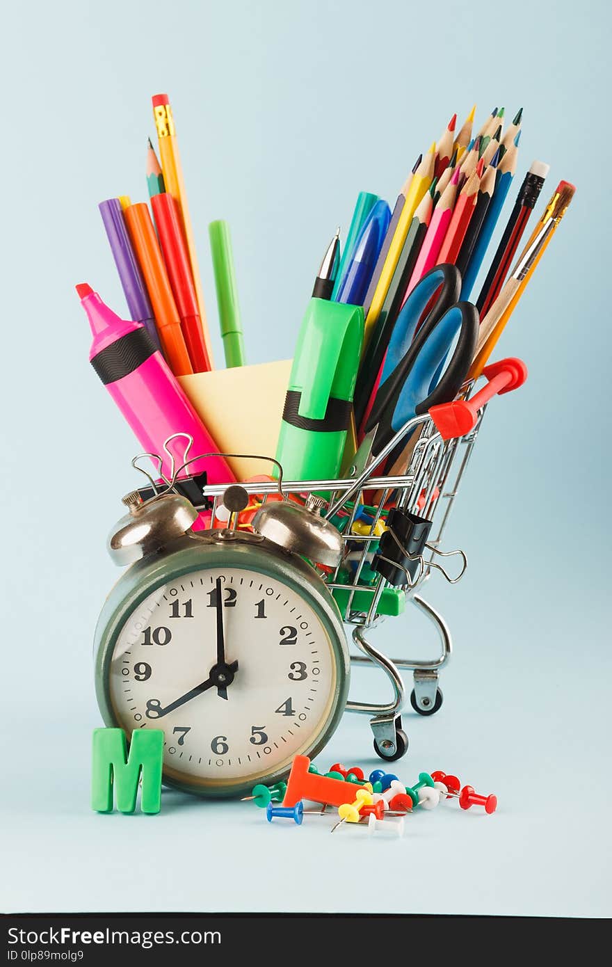 Shopping cart with different stationery on the blue background