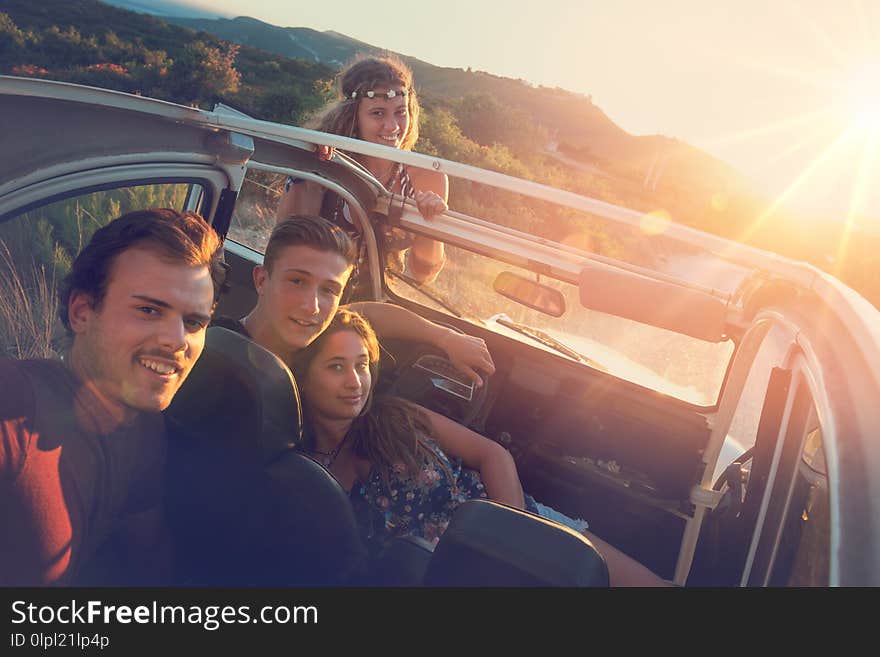 Group of happy people in a car at sunset in summer. Group of happy people in a car at sunset in summer.