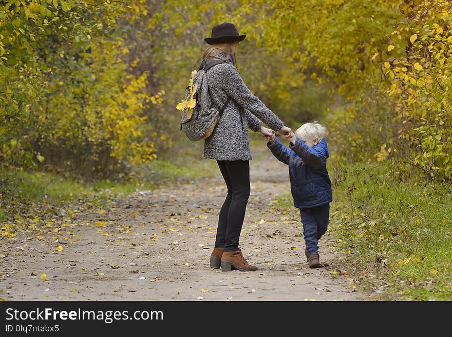 Mom and son are playing in the autumn forest.