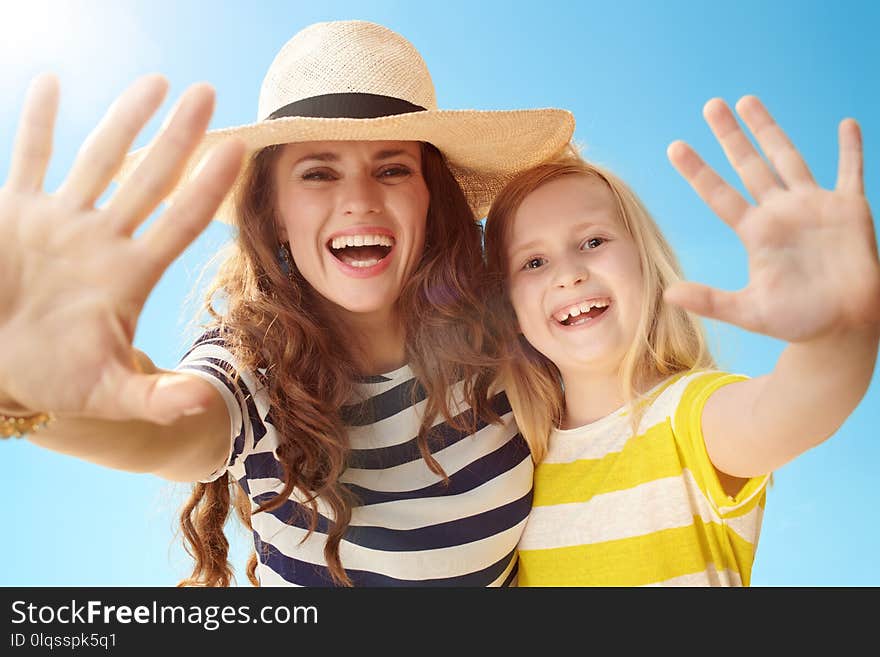 Young mother and daughter greeting against blue sky