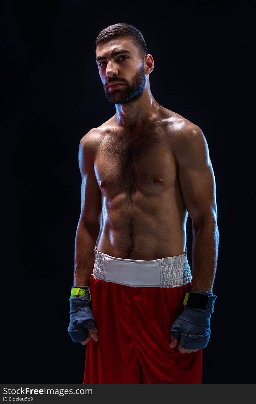 Boxing man ready to fight. Boxer with strong hands and clenched fists in blue straps against a black background. Strength and motivation. Studio shot