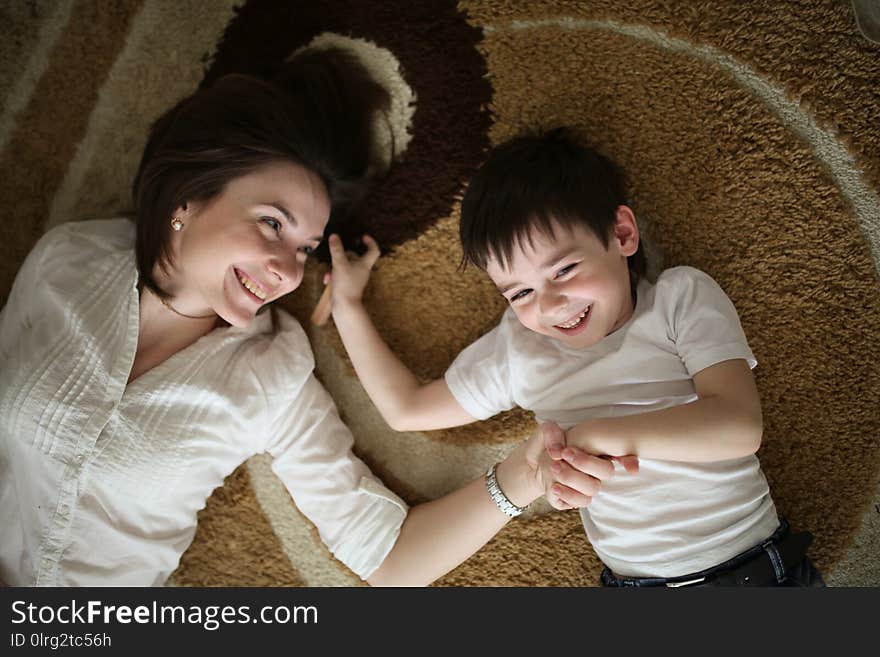 Beautiful brunette mom playing and hugging with her son on the floor in a home-like normal real interior, brown toning, soft focus, top view. Beautiful brunette mom playing and hugging with her son on the floor in a home-like normal real interior, brown toning, soft focus, top view