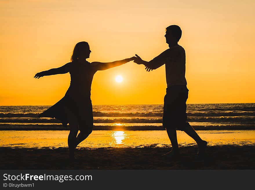 Beautiful silhouettes of two lovers dancers at sunset on a romantic beach with the sea in the background. Latin dances. Beautiful silhouettes of two lovers dancers at sunset on a romantic beach with the sea in the background. Latin dances