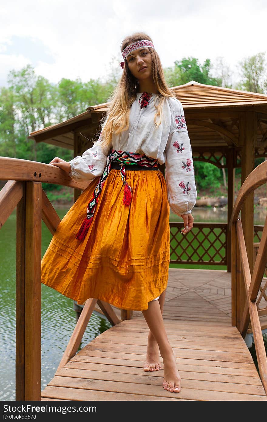 Beautiful slender Ukrainian in embroidery in windy weather enjoys a rest on the lake on a summer sunny day. Beautiful slender Ukrainian in embroidery in windy weather enjoys a rest on the lake on a summer sunny day