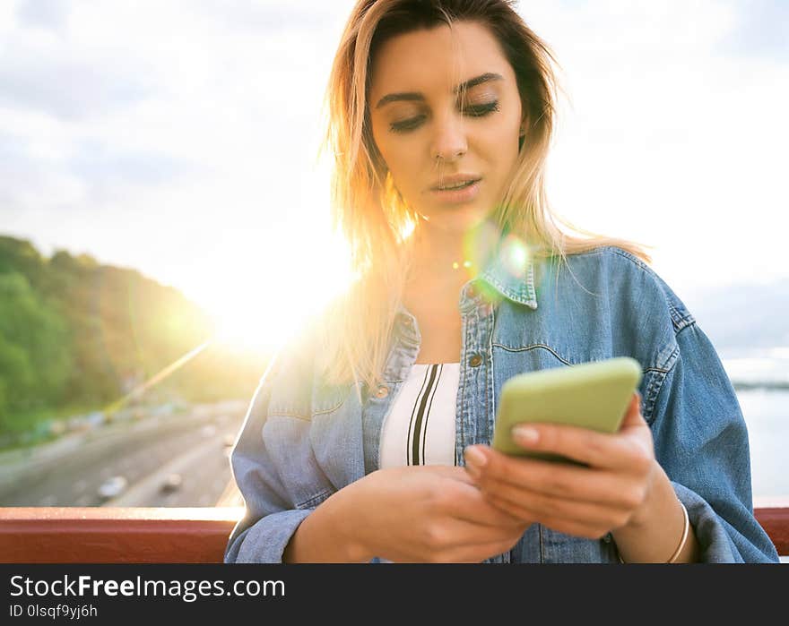 Girl freelancer at sunset speaks on the phone and works