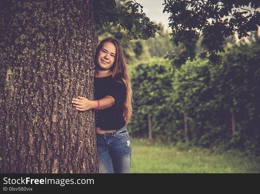 Young girl near tree posing, hugging a tree