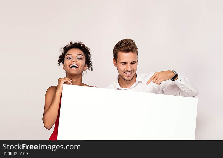 Happy young couple holding white banner with copy space. Man and women with blank board. Happy young couple holding white banner with copy space. Man and women with blank board.