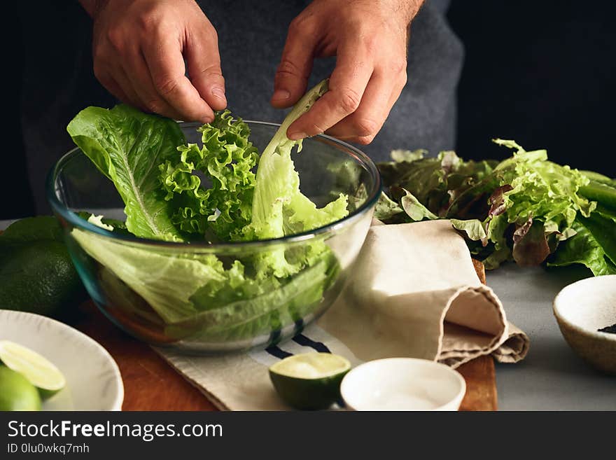 Man is cooking green detox salad of romaine lettuce. Healthy food concept. Man is cooking green detox salad of romaine lettuce. Healthy food concept