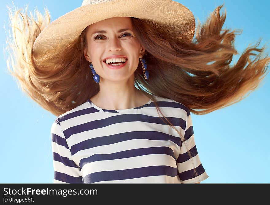 Happy young woman with fluttering hair against blue sky