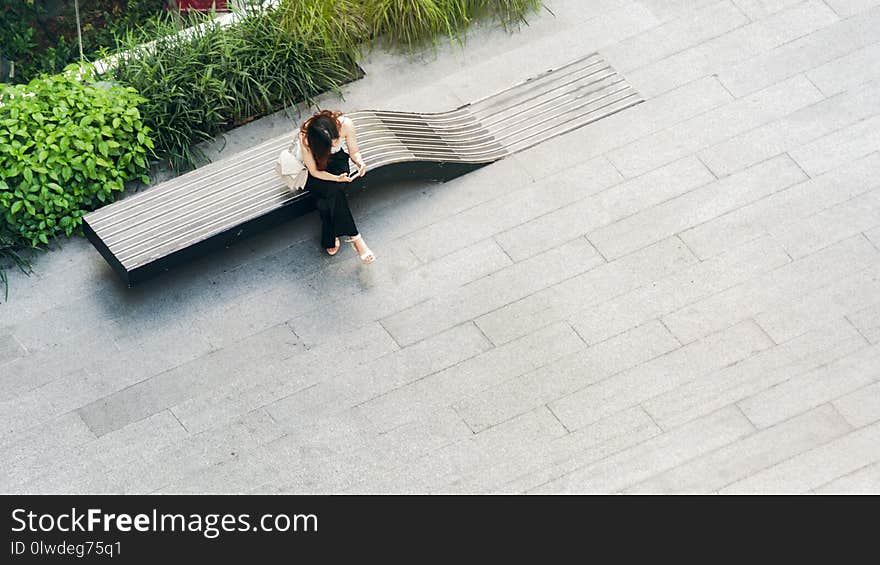 The top aerial view woman uses smartphone sit on wooden bench at walkway pedestrian, concept of social still life.