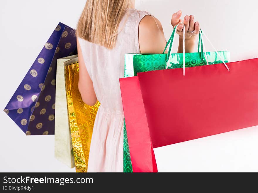 Fashion model girl with shopping colorful bags in hands and cream lace dress