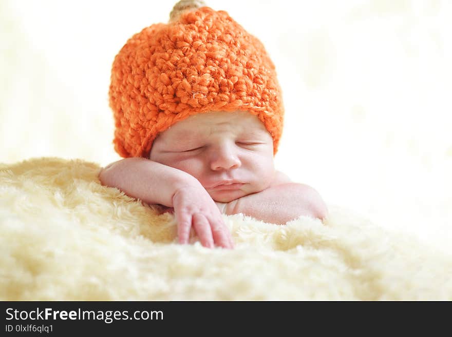 Newborn boy is wearing a pumpkin hat. Newborn boy is wearing a pumpkin hat