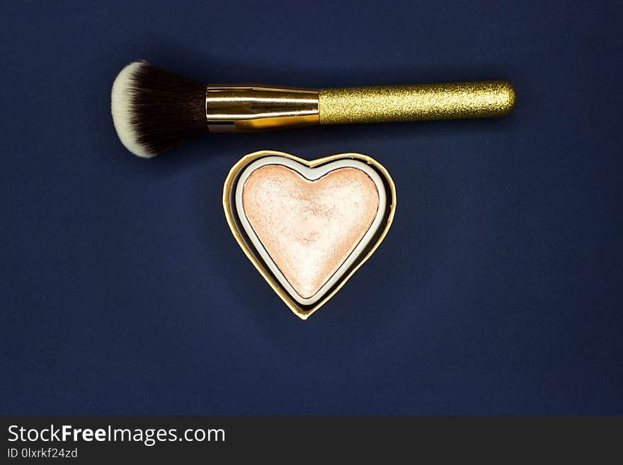 Brush for make-up and powder-gloss on a blue background