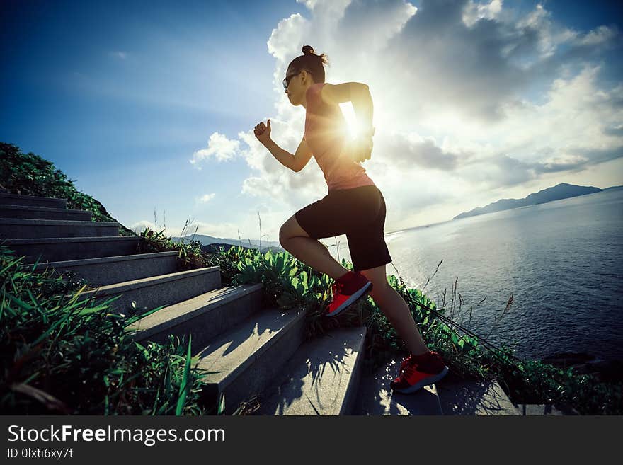 Woman running up on seaside mountain stairs