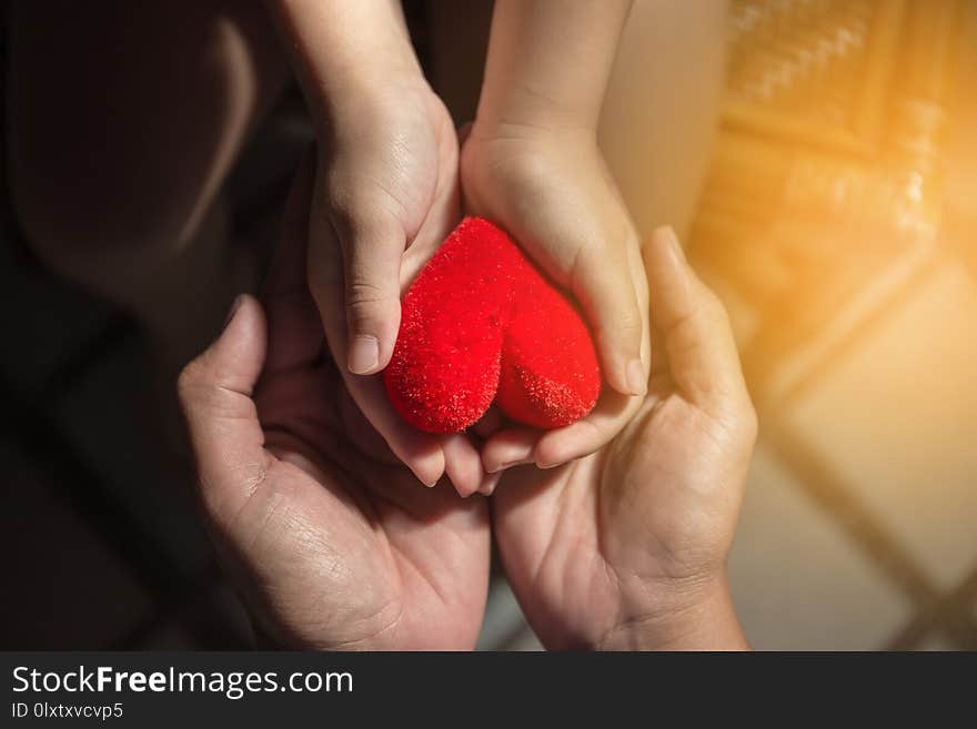 Adults and children are holding a red heart.Happy family relationships and health care concept.