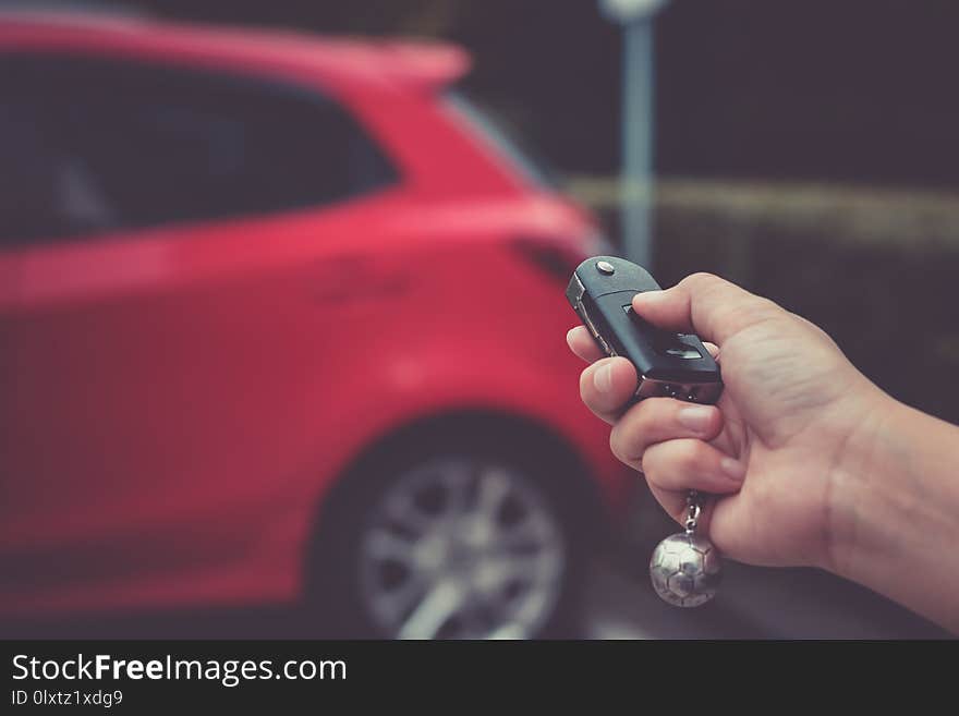 Human hand pushing button on remote control car key