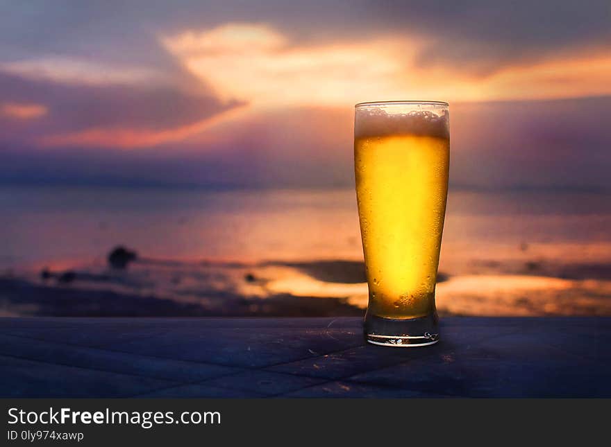 Beer in glass on the beach in sunset. Beer in glass on the beach in sunset