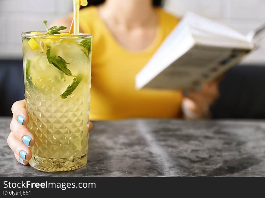 Woman with glass of lemonade at table, closeup