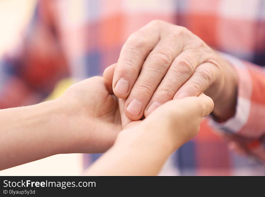 Young woman holding elderly man hand, closeup. Help service