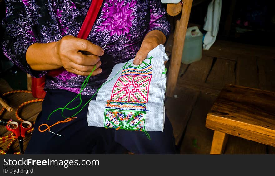 Asian hill tribe woman embroidering traditional handicraft fabric for decorate local homemade clothes.