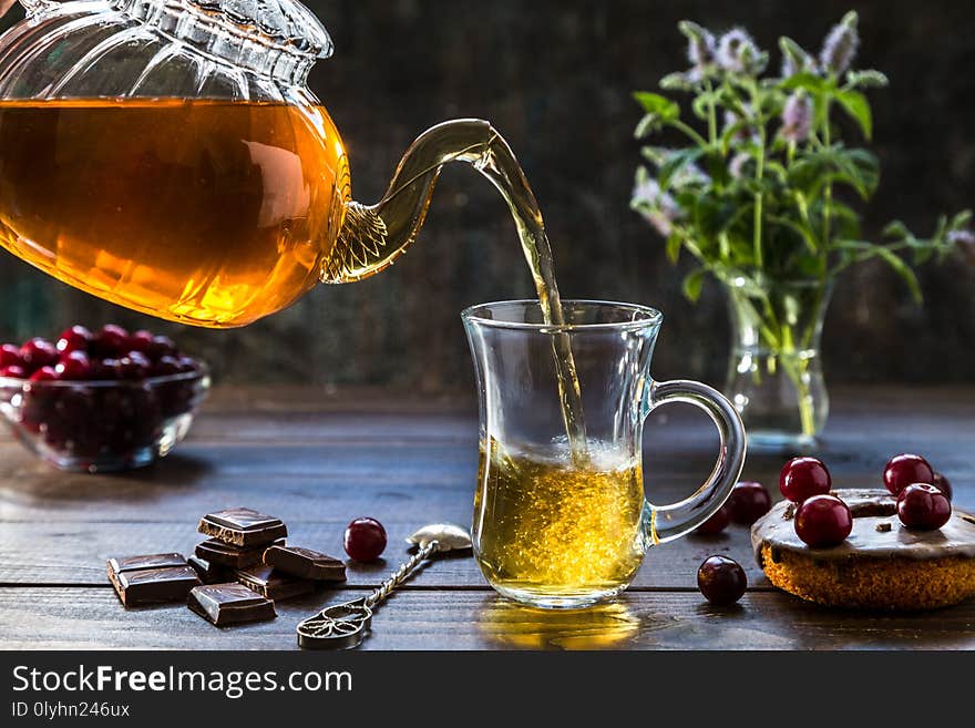 Hot tea pours from a transparent teapot into a glass. Hot tea pours from a transparent teapot into a glass.