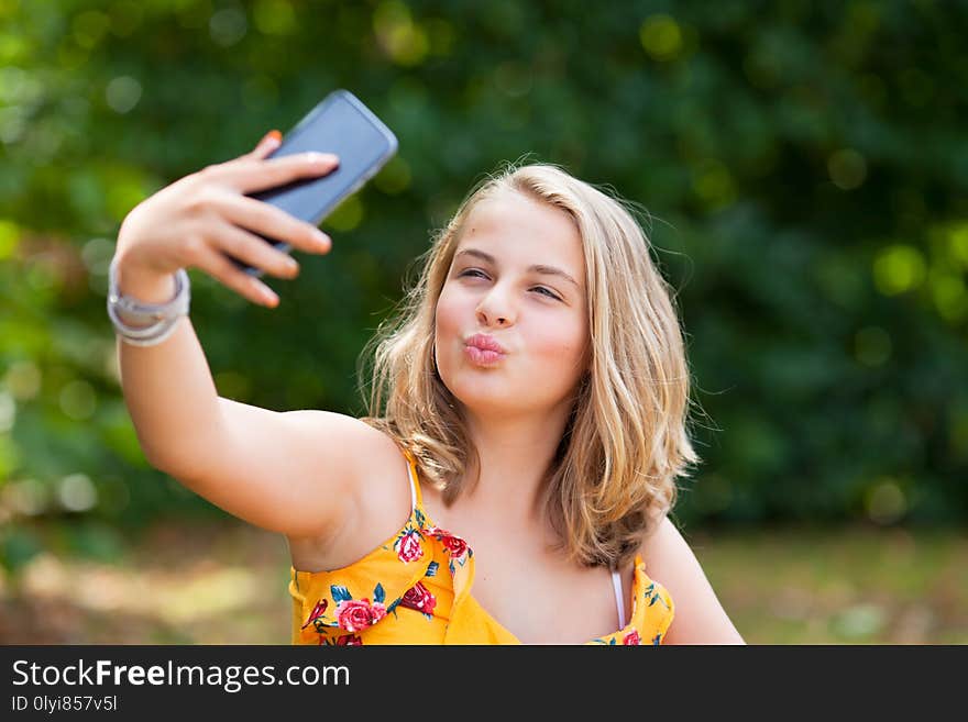 Young girl lin a park with her smartphones making a selfie. Young girl lin a park with her smartphones making a selfie