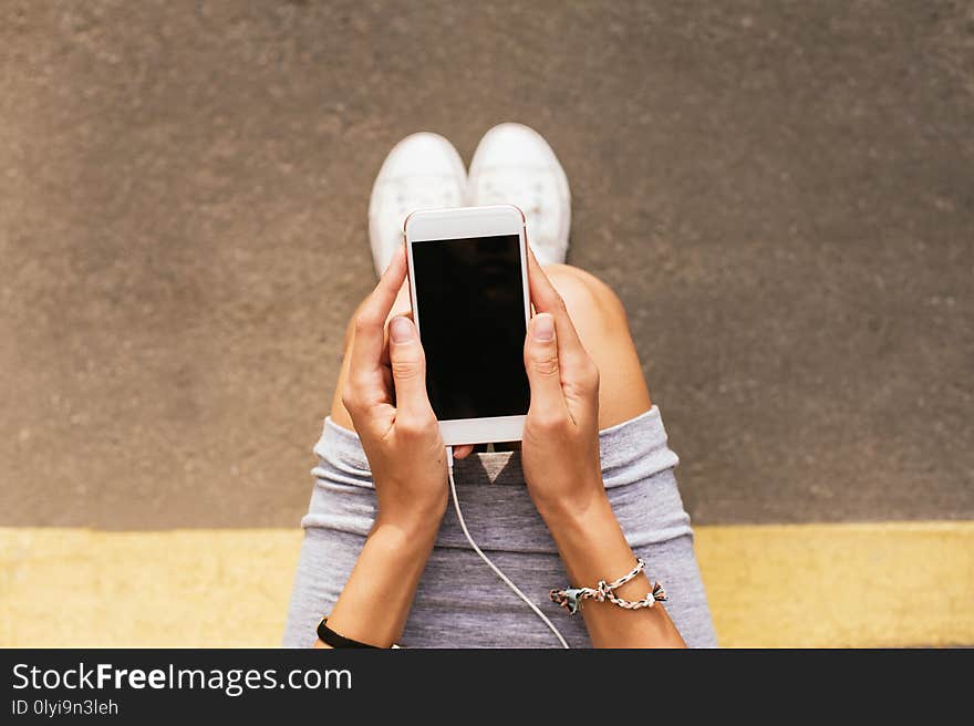 Girl in sneakers sitting on the floor with smart phone in her hands. Girl in sneakers sitting on the floor with smart phone in her hands.