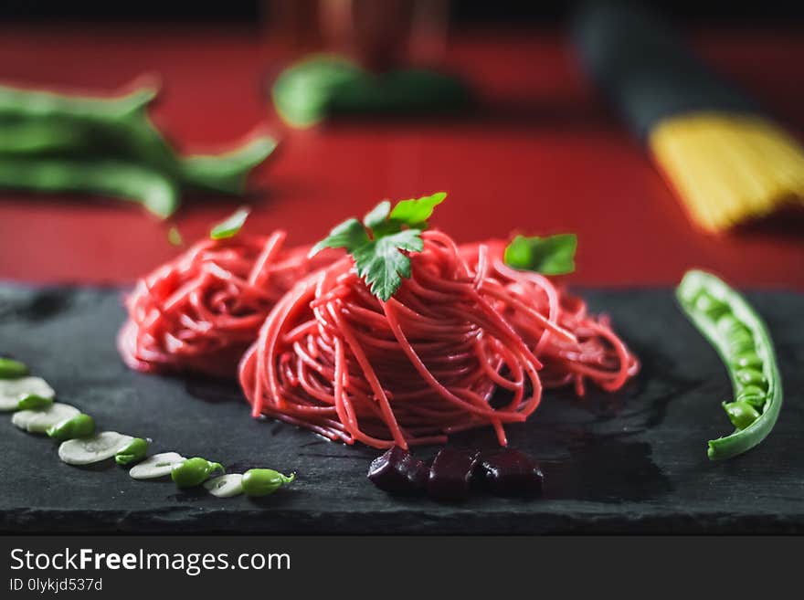 Spaghetti with beetroot, red beans and parsley on black slate and red marble base. Spaghetti with beetroot, red beans and parsley on black slate and red marble base