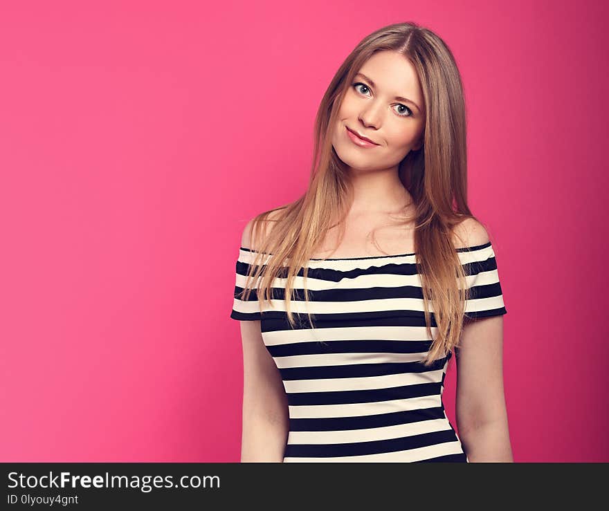 Beautiful smiling blond long stright hairstyle woman in striped dress presenting something on pink background. Closeup portrait with empty copy space