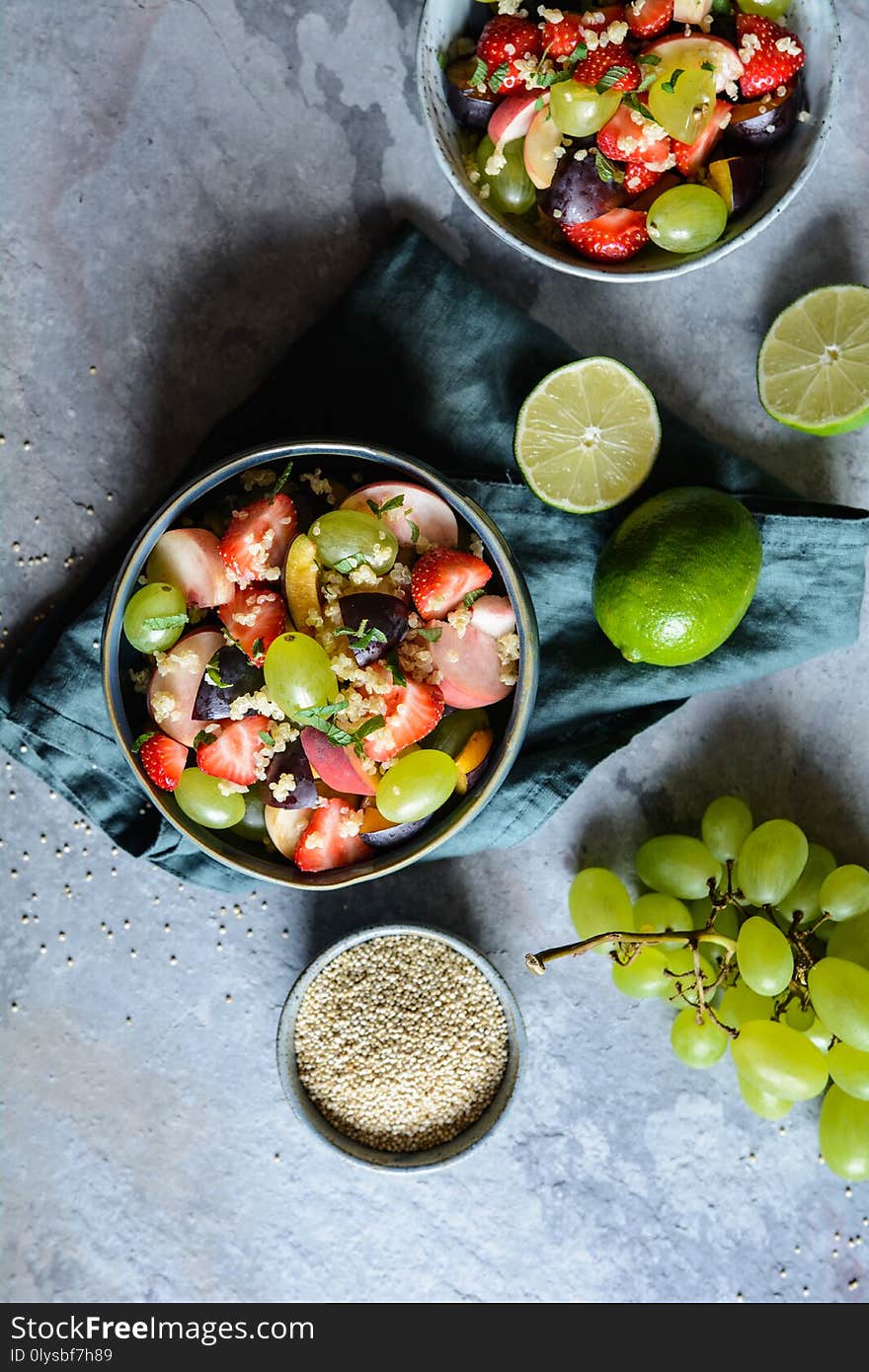 Healthy fruit salad with quinoa, strawberry, peach, white grapes, plums, mint and honey lime dressing