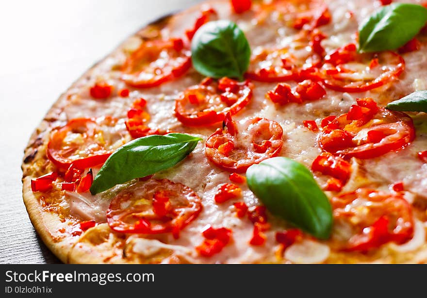 Pizza with Mozzarella cheese, Ham, Tomatoes, pepper, Spices and Fresh Basil. Italian pizza on wooden background.