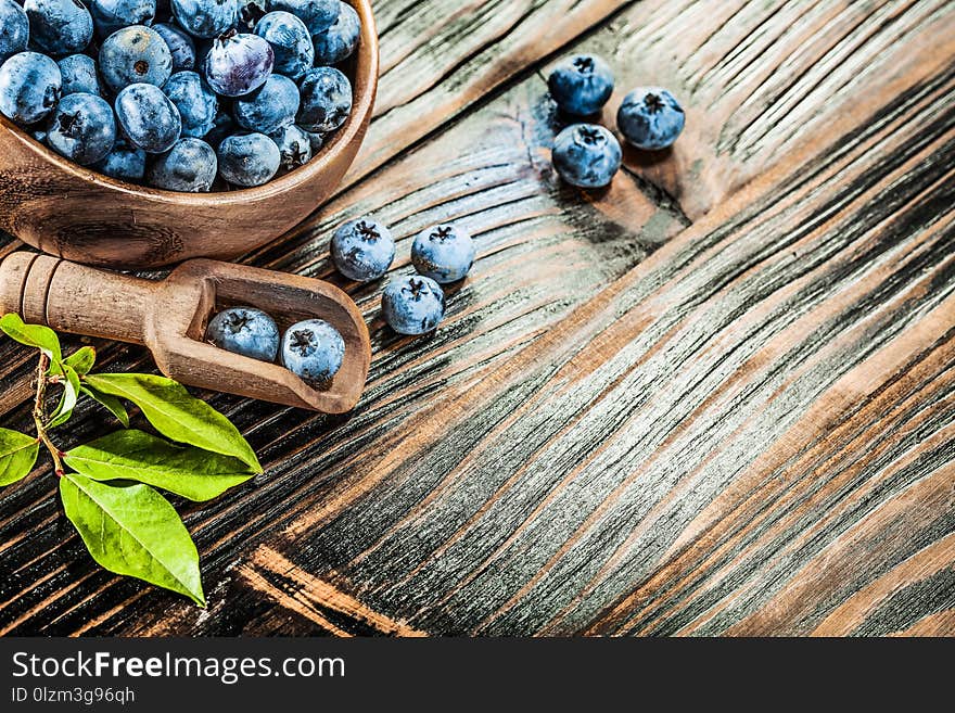 Ripe huckleberries in wooden spoon bowl.