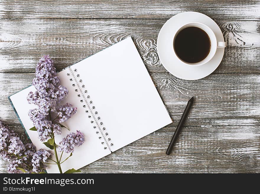 Top view of a diary or notebook, pencil and coffee and a purple flower on a gray wooden table. Flat design.