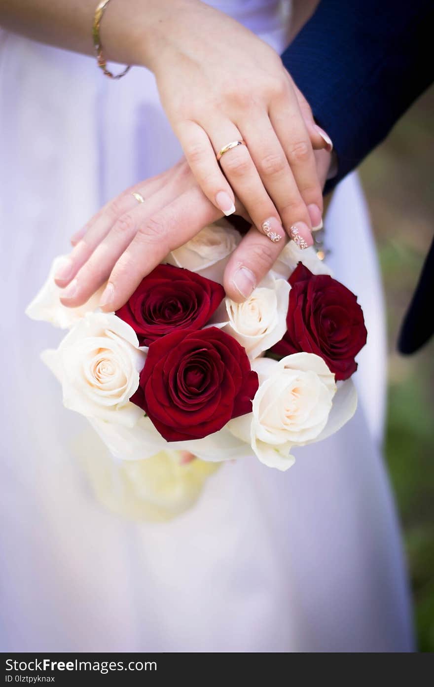 Wedding bouquet of red roses in the hands of the bride and groom