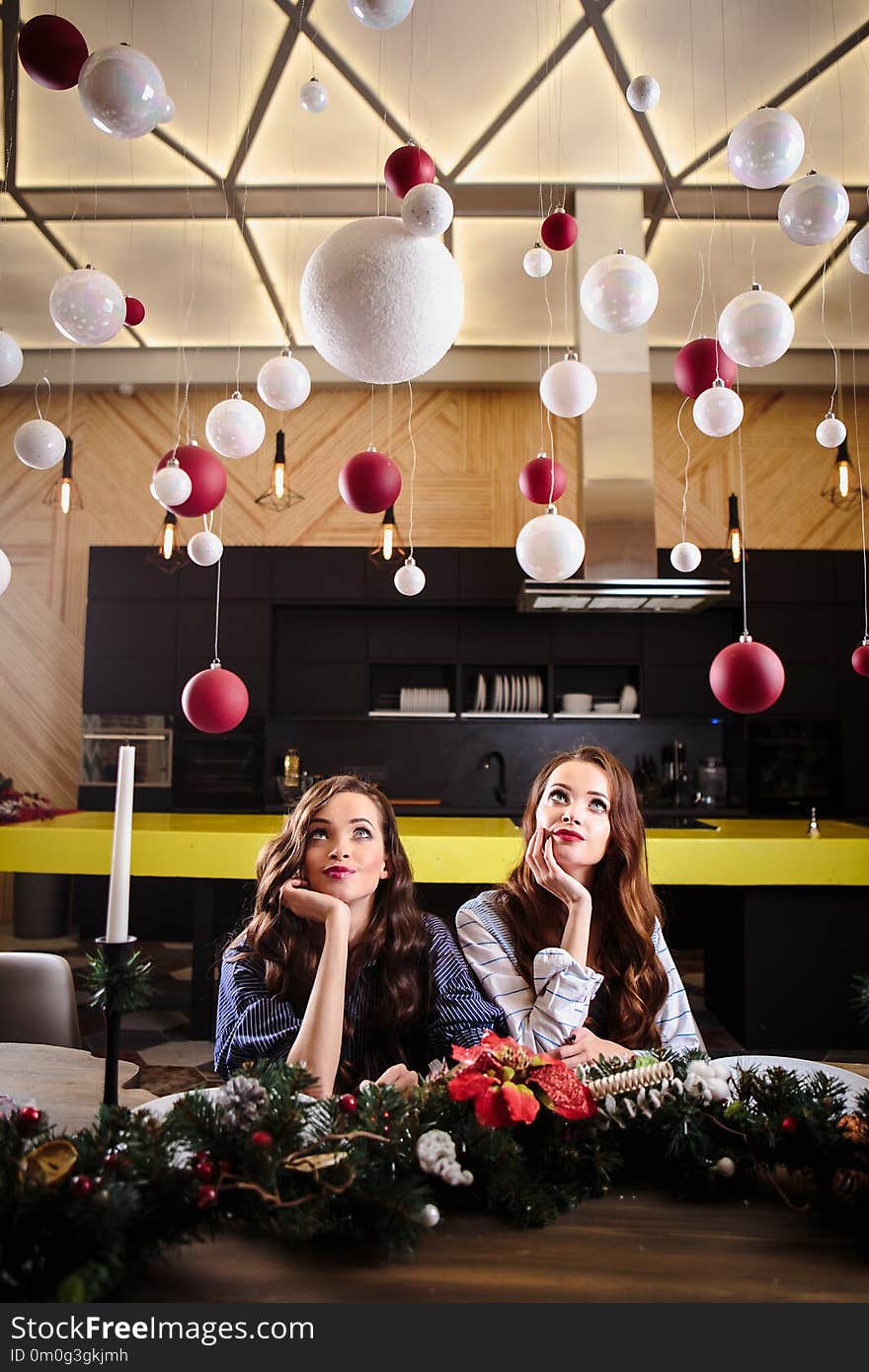 Pretty twins young women together in a kitchen room, casual home style, new year and christmas decorations