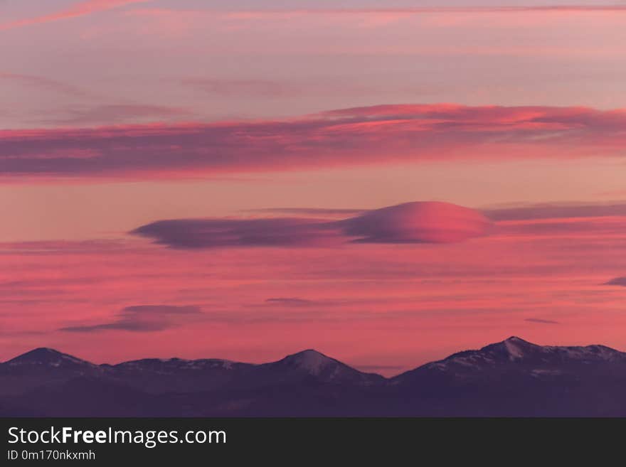 A View Of Some Mountains Top, Beneath A Beautiful, Warm Colored Sky At Sunset