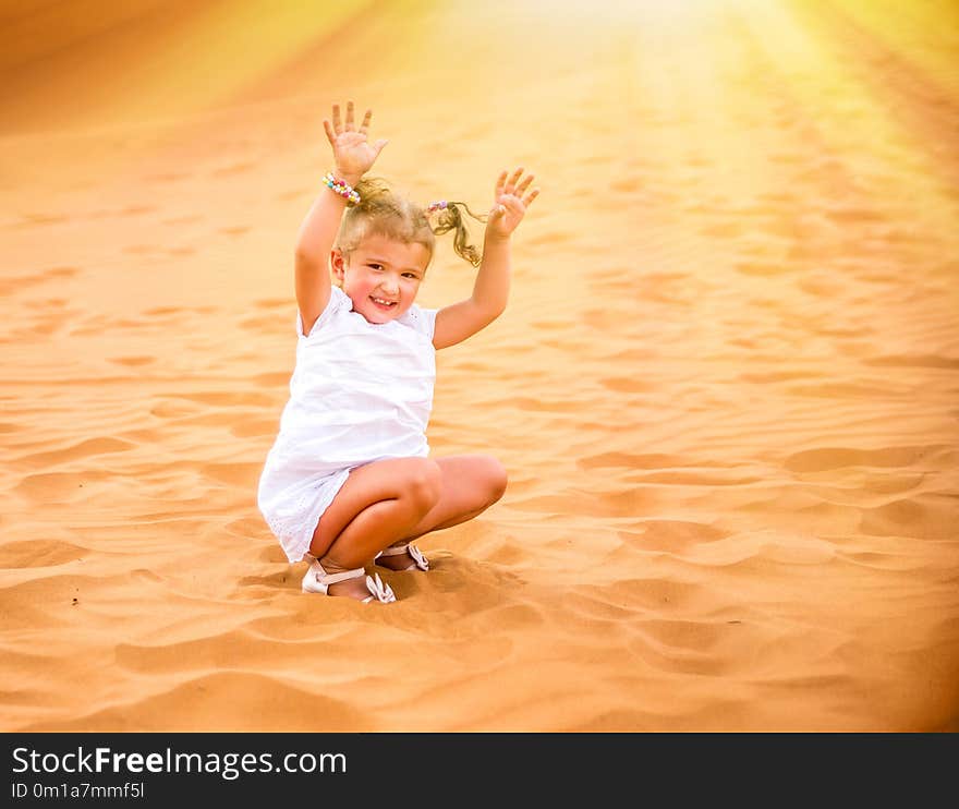 Little girl smiles and plays sand