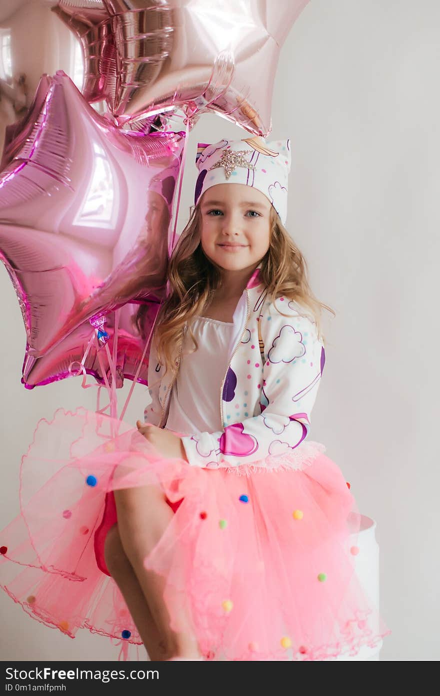 Little beautiful happy girl in a fashionable dress in the studio