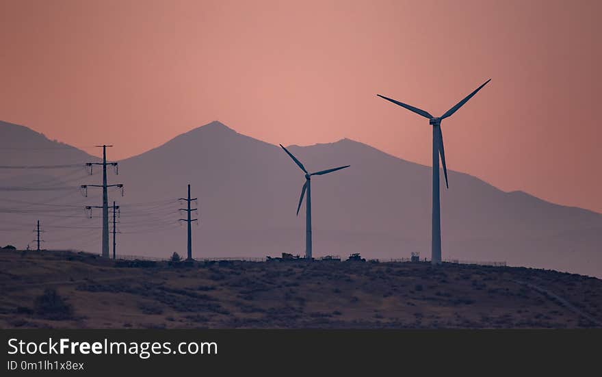 Large ind turbines generating electricity in the sunset wind and the mountains in the background. Large ind turbines generating electricity in the sunset wind and the mountains in the background